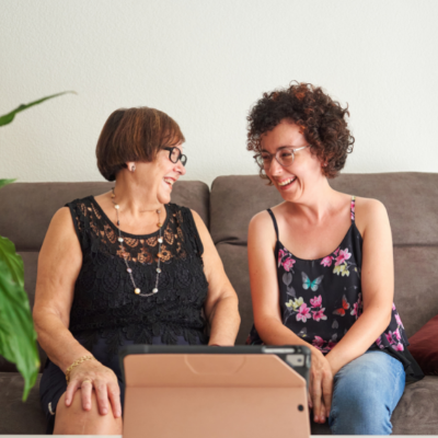 two women sitting on a sofa smiling at each other