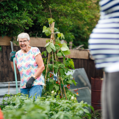 a woman holding a gardening tool next to a tomato plant