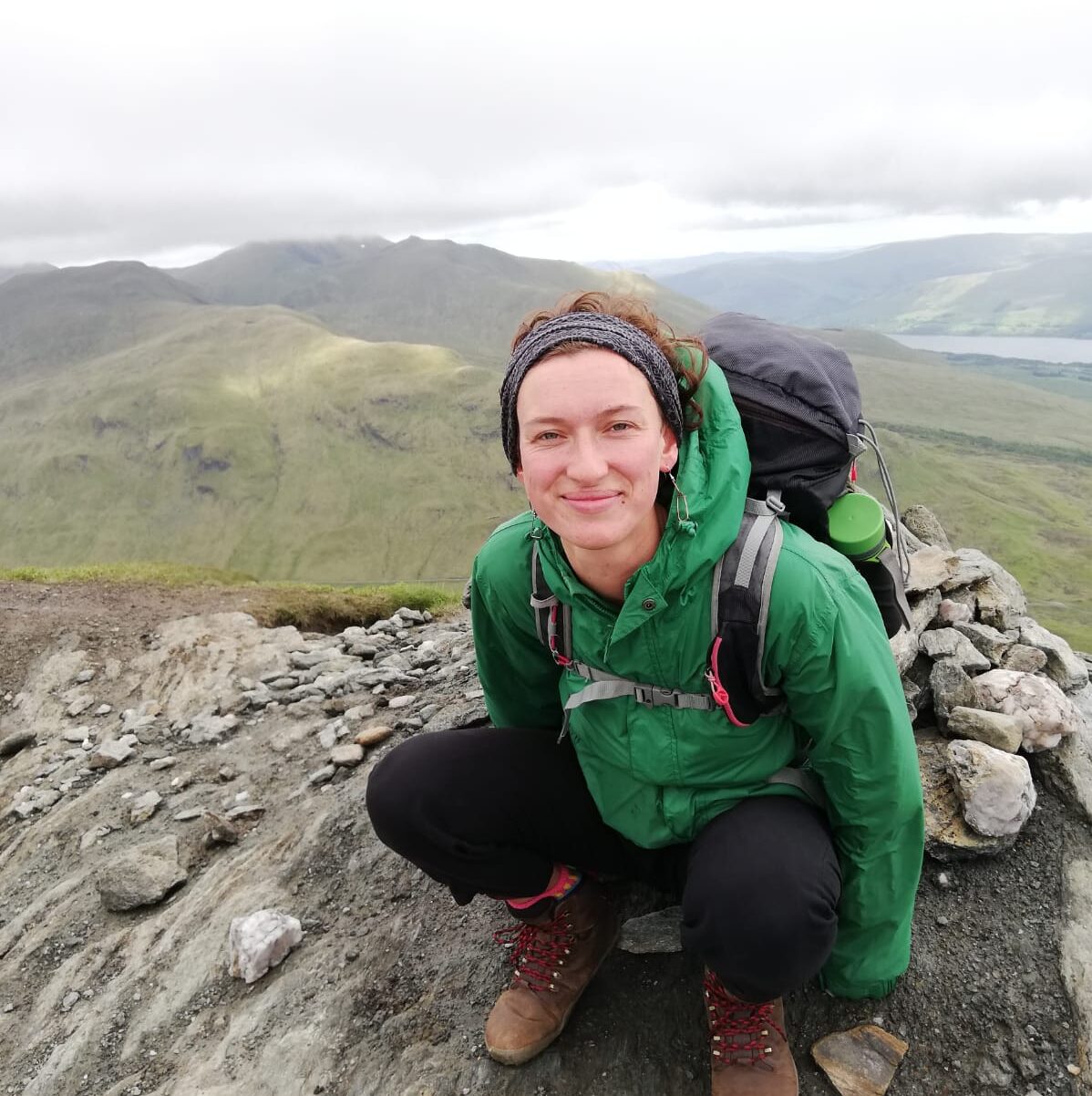 picture of someone crouching on top of a mountain smiling